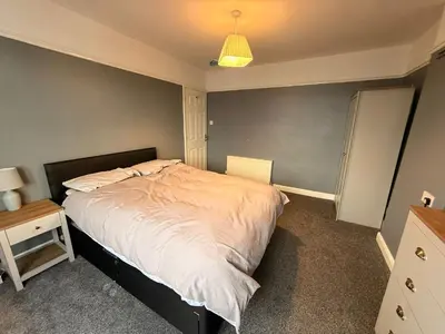 a bedroom with a bed and a table and a lamp at Sanders Grove in Morecambe