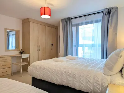 a bedroom with a bed and a desk and a window at Spacious 2-Bedroom Apt in Heart of City Centre in Liverpool