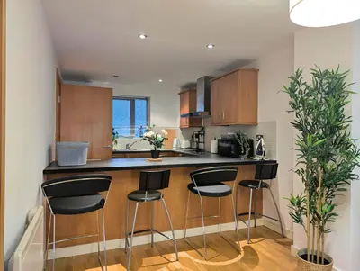 a kitchen with a bar with four stools at Spacious 2-Bedroom Apt in Heart of City Centre in Liverpool