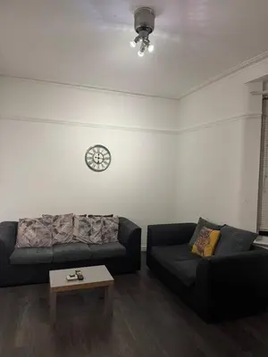 a living room with two couches and a clock on the wall at The Fabulous Gem in Wallasey in Wallasey