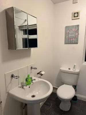 a white bathroom with a toilet and a sink at The Fabulous Gem in Wallasey in Wallasey