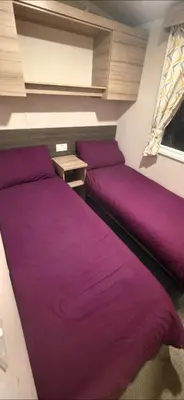 two beds in a room with purple sheets at Sea view 1 in Heysham