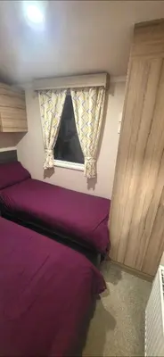 a bedroom with purple beds and a window at Sea view 1 in Heysham
