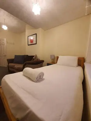 a bedroom with a large white bed and a couch at Warm & Welcoming Balfour Getaway in Wallasey