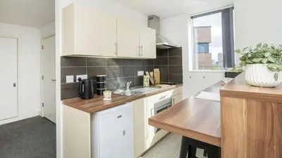 a kitchen with white cabinets and a wooden table at For Students Only Windsor Court in Liverpool in Liverpool
