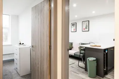 an open door to a room with a kitchen and a desk at Dreams stay in Preston
