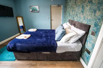 a bedroom with a bed with a blue wall at Soho Duplex Promenade Seaview Apartment in Blackpool
