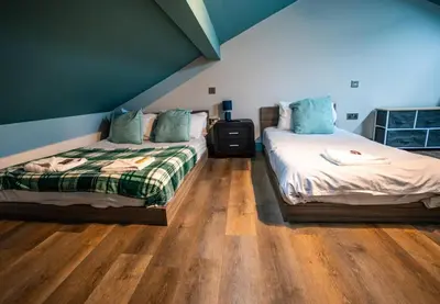 a bedroom with two beds and a wooden floor at Soho Duplex Promenade Seaview Apartment in Blackpool