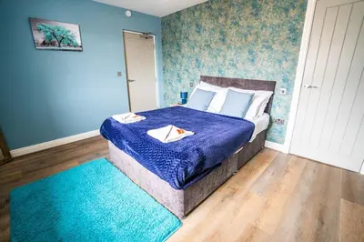 a bedroom with a bed with a blue comforter at Soho Duplex Promenade Seaview Apartment in Blackpool