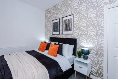a bedroom with a bed with orange pillows and a wallpaper at Modern 3BR House in Liverpool - Garden in Liverpool
