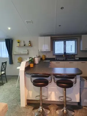 a kitchen with a counter with two bar stools at Jasper Lodge in Morecambe