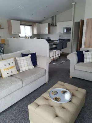 a living room with two couches and a kitchen at Jasper Lodge in Morecambe