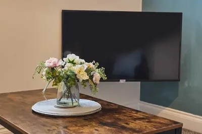 a vase of flowers sitting on a table with a tv at Host & Stay - Showtime Studio in Blackpool