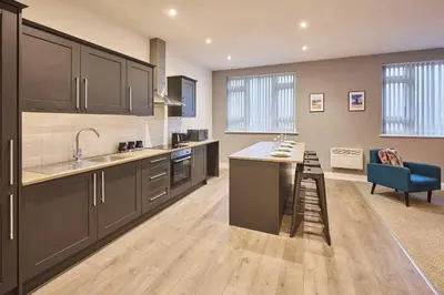 a kitchen with black cabinets and a blue chair at Host & Stay - Illumination Suite in Blackpool