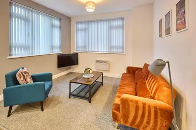 a living room with a couch and a table and a tv at Host & Stay - Illumination Suite in Blackpool