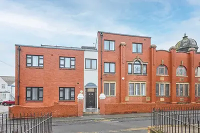 a red brick building with a black door at Host & Stay - Sandcastle Apartment in Blackpool
