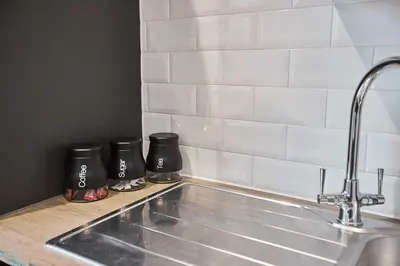 a kitchen sink with two black coffee mugs on a counter at Host & Stay - Promenade Suite in Blackpool