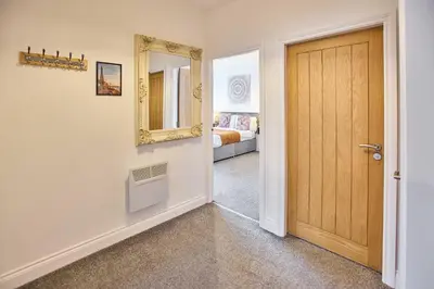a hallway with a door and a mirror and a bed at Host & Stay - Promenade Suite in Blackpool