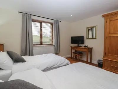 a bedroom with two beds and a tv and a window at 6 Swan House in Carnforth