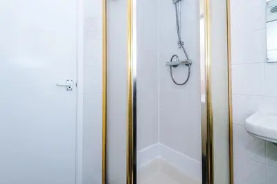a shower with a glass door next to a sink at Derwent Holiday Hotel in Blackpool