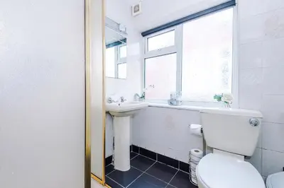 a bathroom with a toilet and a sink and a window at Derwent Holiday Hotel in Blackpool