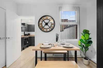 a kitchen with a table and a clock on the wall at Large 4BR House - Sleeps 7 - Long Stays Great Location in Litherland