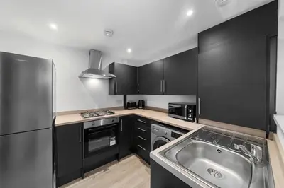 a kitchen with black cabinets and a stainless steel sink at Large 4BR House - Sleeps 7 - Long Stays Great Location in Litherland