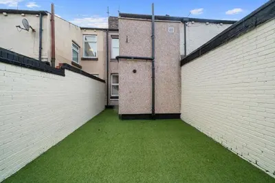 an alley with white brick walls and green grass at Large 4BR House - Sleeps 7 - Long Stays Great Location in Litherland