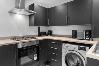 a kitchen with black cabinets and a washing machine at Large 4BR House - Sleeps 7 - Long Stays Great Location in Litherland