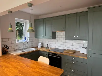 a kitchen with green cabinets and a wooden counter top at Seaside escape near Cartmel and Grange in Kents Bank