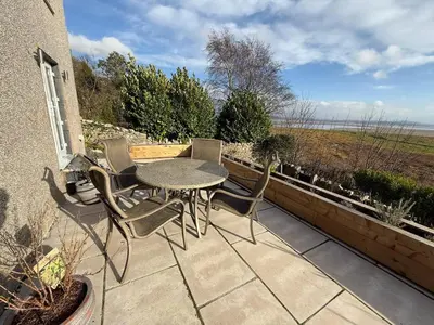 a patio with a table and chairs on a balcony at Seaside escape near Cartmel and Grange in Kents Bank