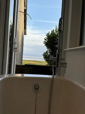 a bath tub in a bathroom with a view of the ocean at Seaside escape near Cartmel and Grange in Kents Bank
