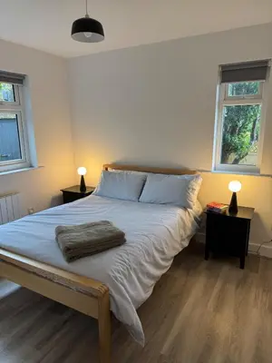 a bedroom with a large bed with two windows at Seaside escape near Cartmel and Grange in Kents Bank