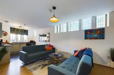 a living room with two blue couches and a kitchen at Luna Church 5 Blackpool in Blackpool