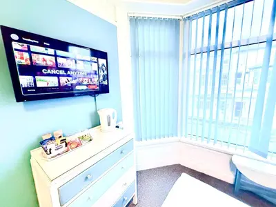 a bedroom with a tv and a dresser and a window at Cherish Lewis Hotel Blackpool in Blackpool