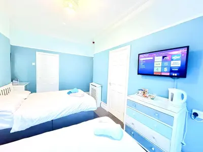 a bedroom with two beds and a tv on the wall at Cherish Lewis Hotel Blackpool in Blackpool