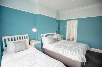 two beds in a room with blue walls at Cherish Lewis Hotel Blackpool in Blackpool