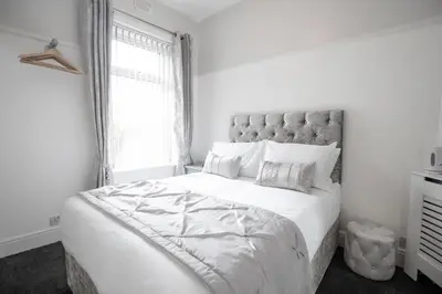 a white bedroom with a large bed and a window at Cherish Lewis Hotel Blackpool in Blackpool
