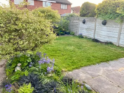 a backyard with a fence and a garden with purple flowers at Modern Bungalow Family Friendly and Eco-Conscious in Southport