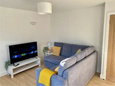 a living room with a blue couch and a flat screen tv at Modern Bungalow Family Friendly and Eco-Conscious in Southport