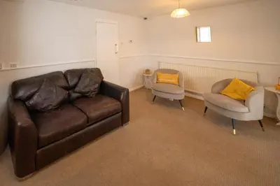 a living room with a leather couch and two chairs at Spacious 3BR House By Kammili Properties in Westhoughton - Free Parking in Westhoughton