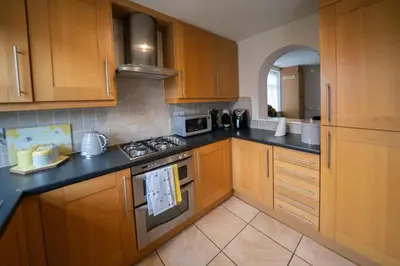 a kitchen with wooden cabinets and a stove top oven at Spacious 3BR House By Kammili Properties in Westhoughton - Free Parking in Westhoughton