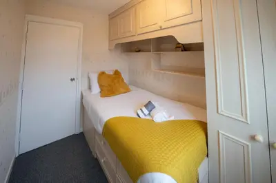 a small bedroom with a yellow bed and cabinets at Spacious 3BR House By Kammili Properties in Westhoughton - Free Parking in Westhoughton