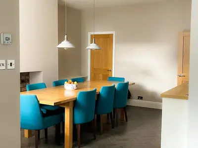 a dining room with a wooden table and blue chairs at Design-inspired, Stunning Clitheroe Home in Clitheroe