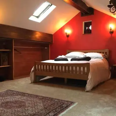a bedroom with a bed with a red wall at Artie's Lodge in Arnside