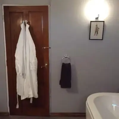 a bathroom with a white robe hanging on a door at Artie's Lodge in Arnside