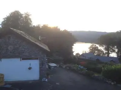 a stone building with a white garage next to a lake at Artie's Lodge in Arnside