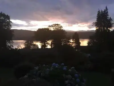 a sunset over a lake with a bunch of flowers at Artie's Lodge in Arnside