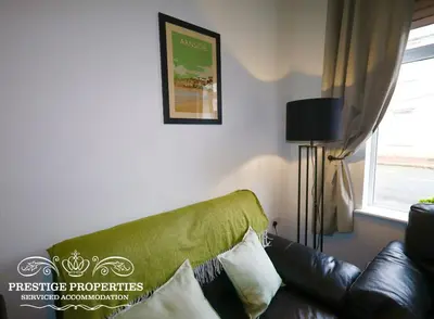 a green couch in a living room with a window at 30 Telford St by Prestige Properties SA in Barrow in Furness