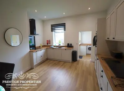 a kitchen with white cabinets and a wooden floor at 30 Telford St by Prestige Properties SA in Barrow in Furness